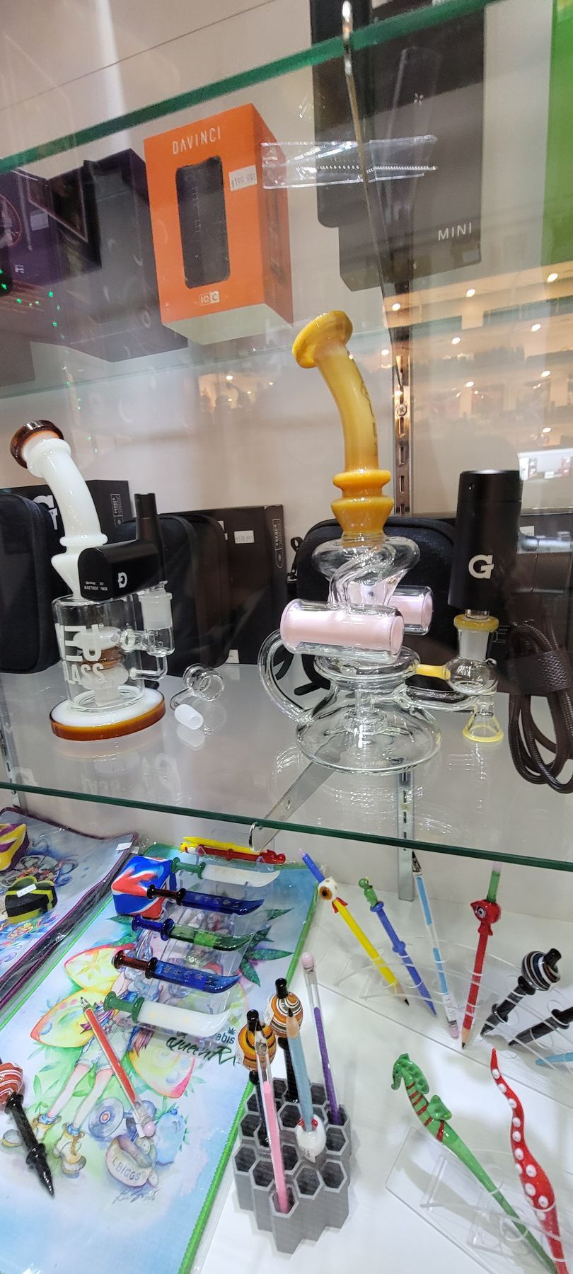 Glass bongs and smoking accessories displayed in a glass case at a store.
