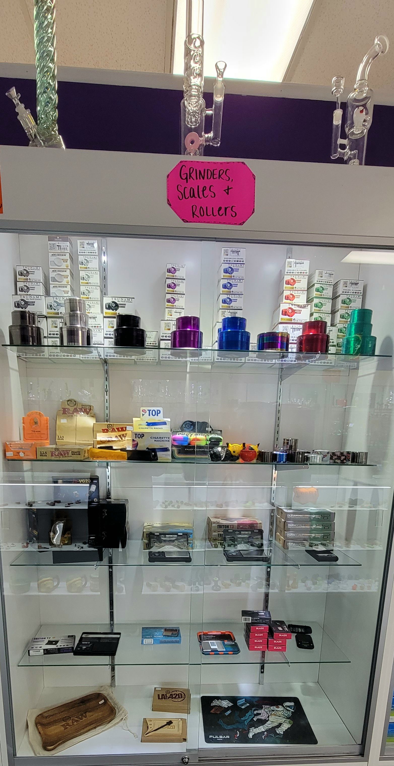A glass display case in a store filled with smoking pipes and accessories. Sign reads 