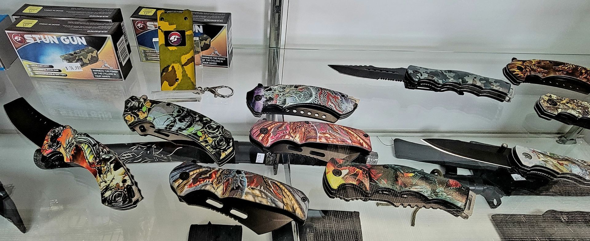 Display case with several camouflage knives.