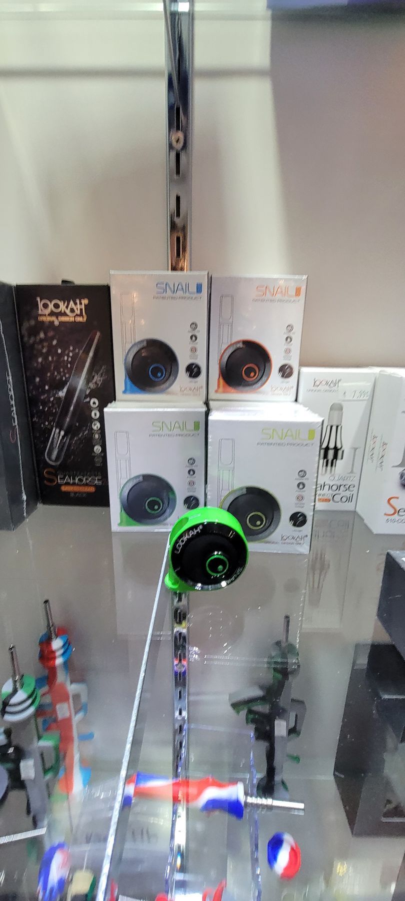 Green device with black circle, four white boxes on display shelf.
