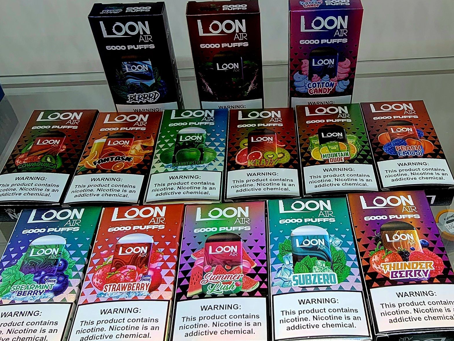 Boxes of Loon 4.5 disposable vapes in various fruit flavors, displayed on a shelf.