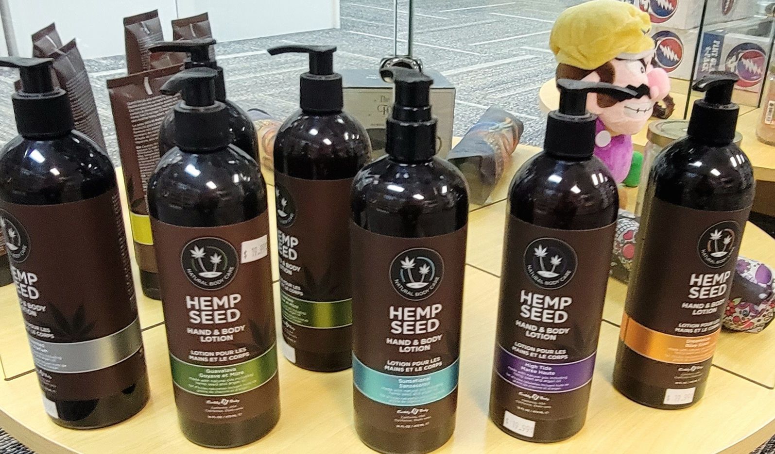 Bottles of hemp seed hair and body products displayed on a table; various colors on labels and pump tops.