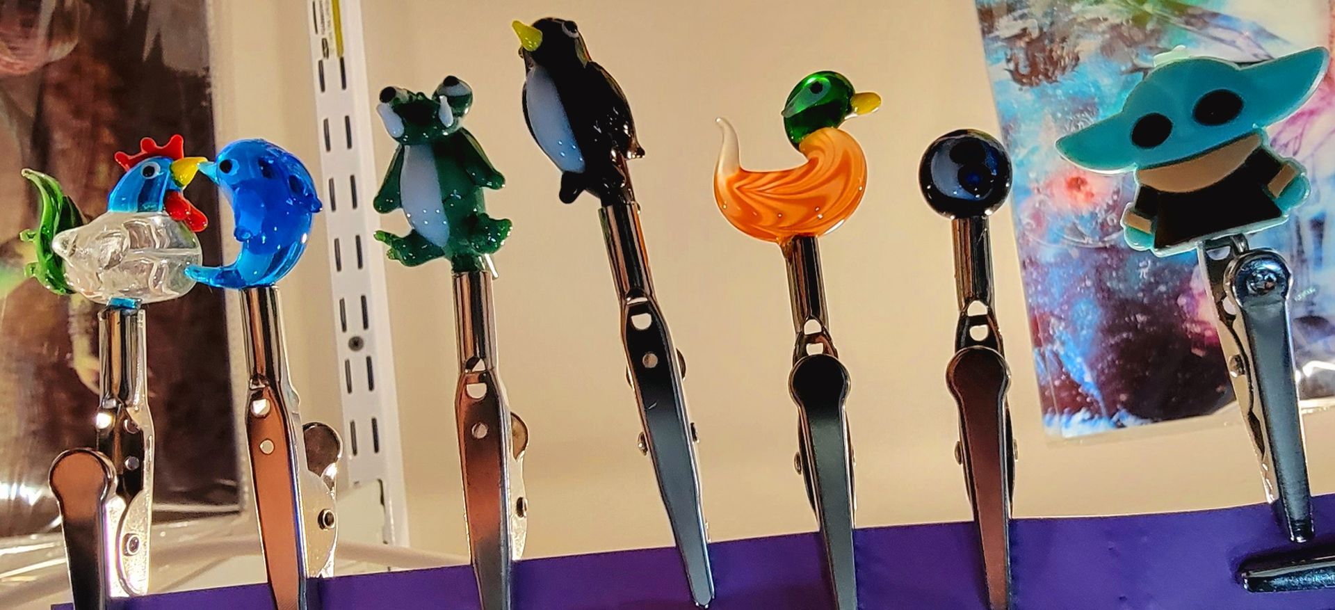 Craft clip holders with various animal and character toppers, on a purple surface.