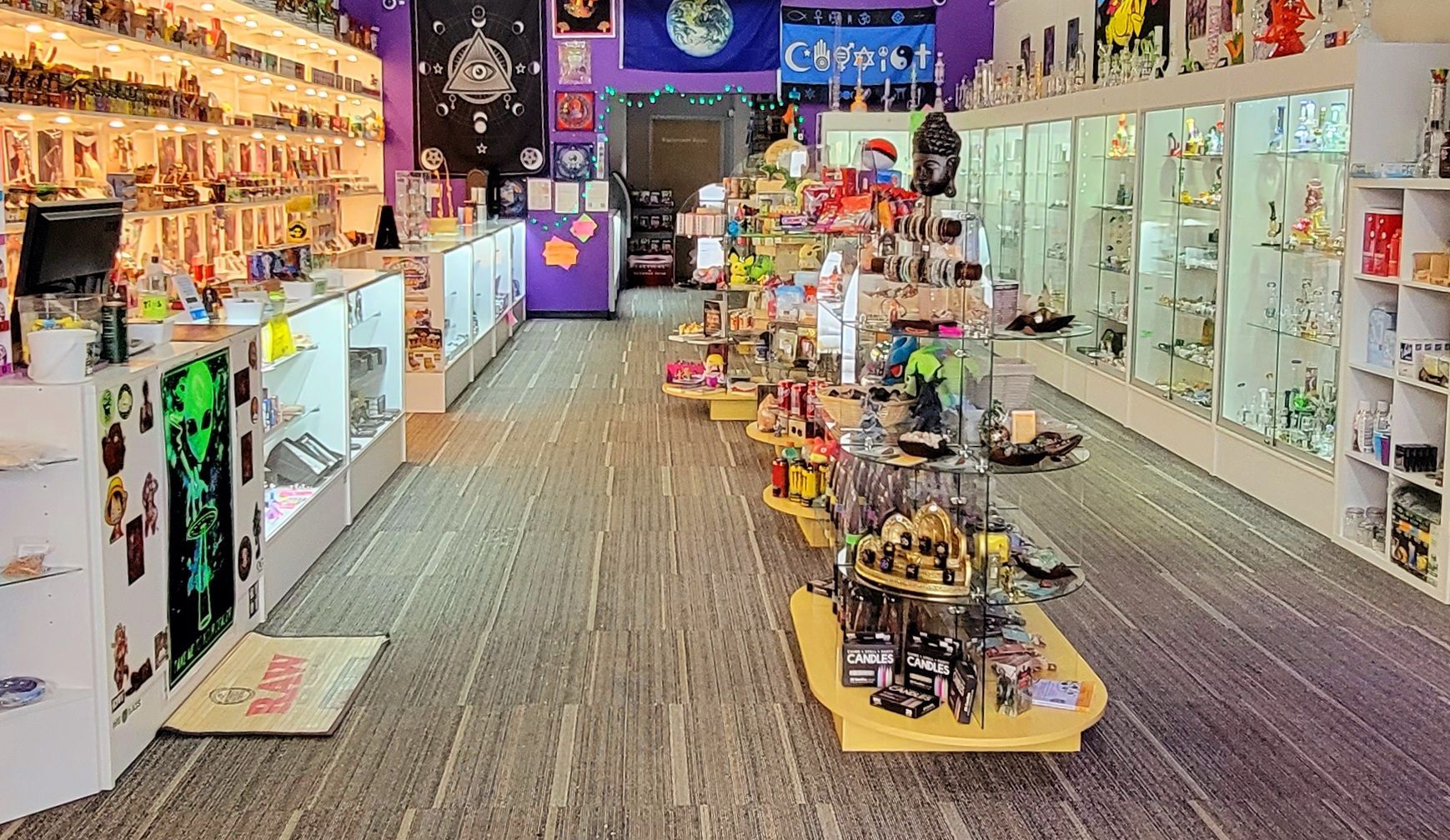 Inside a brightly lit store, shelves display merchandise. Rows of products line the walls and central displays.