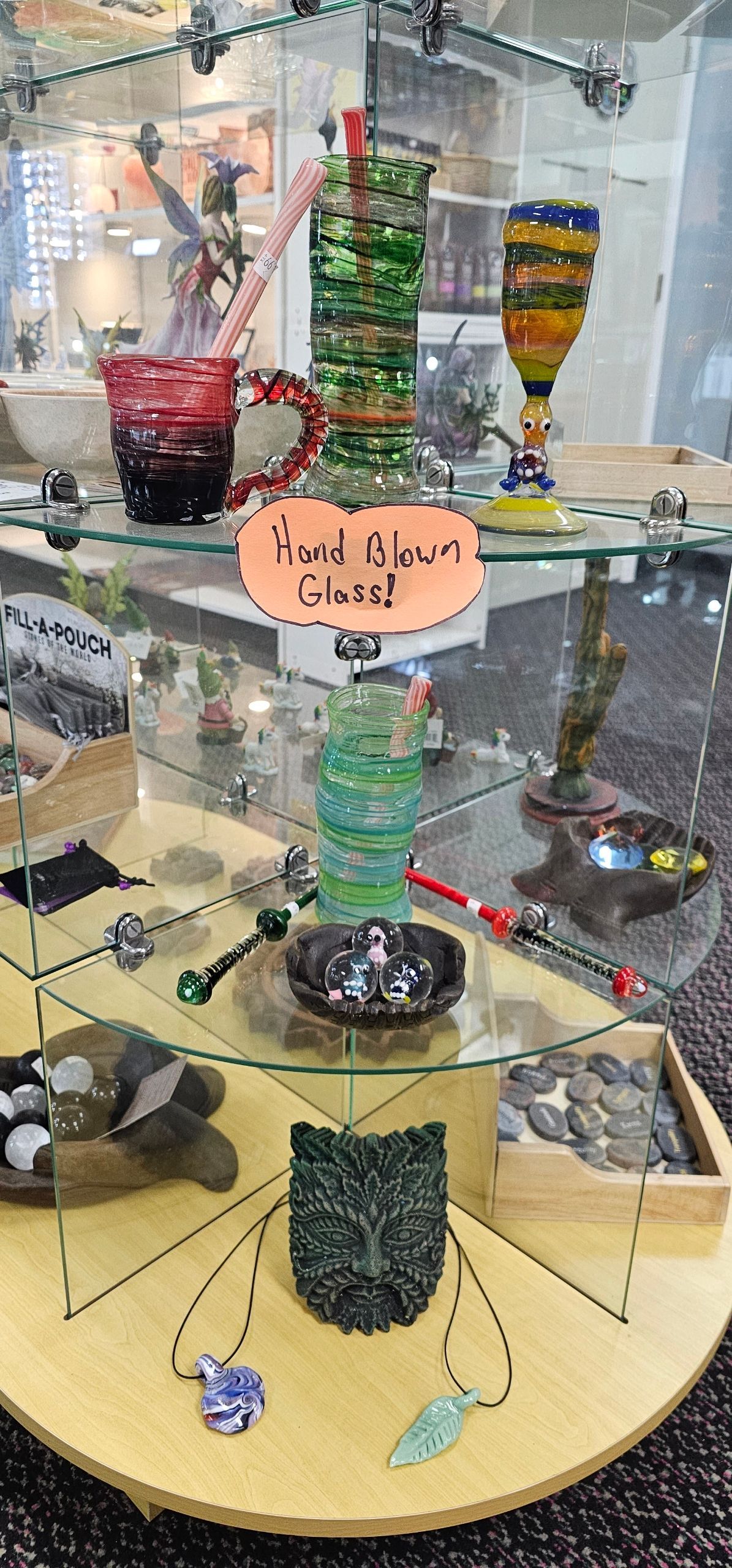 Glassware display in a store. It includes pipes, cups, and jewelry on shelves, in a glass case.