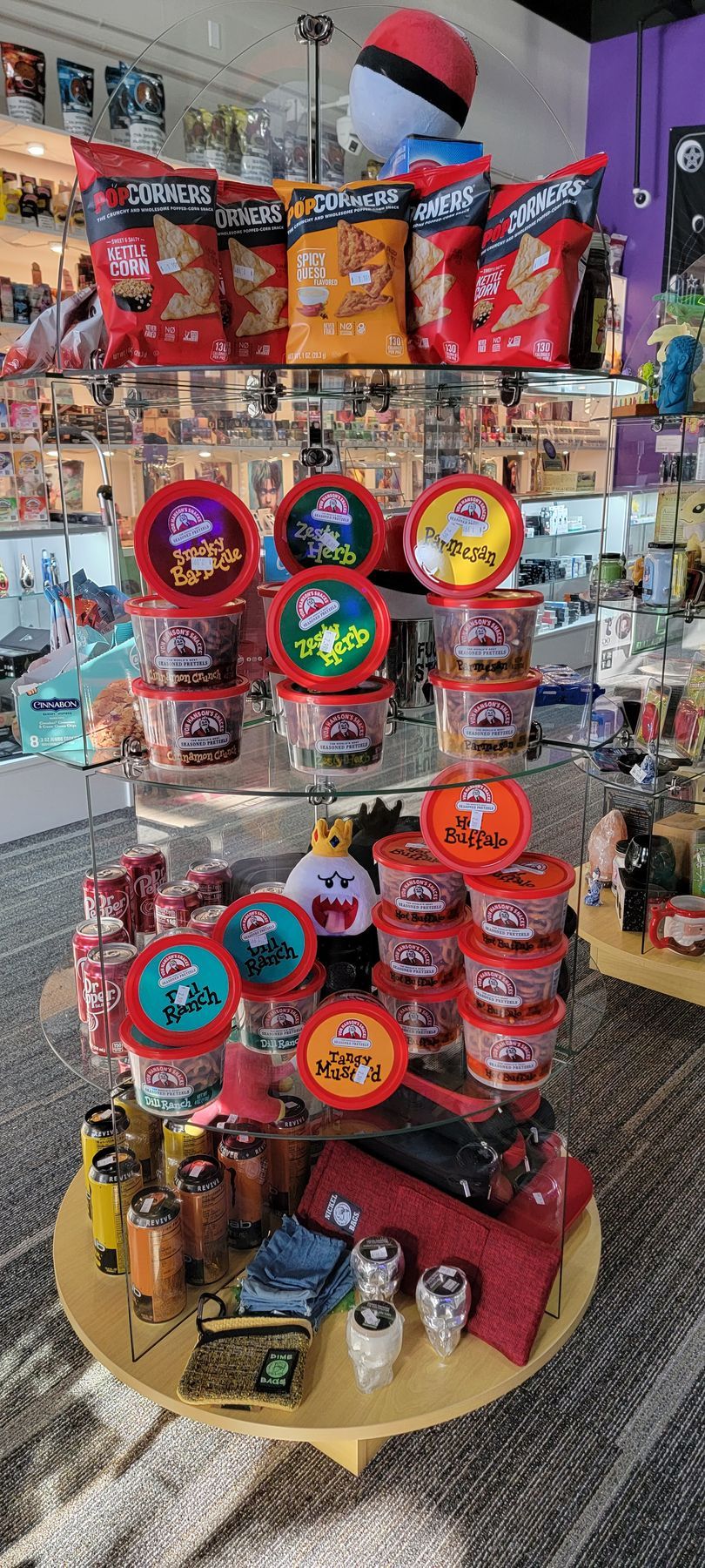 A store display featuring Pokémon-themed snacks and merchandise. Chips, cups, and other items arranged on a round table.