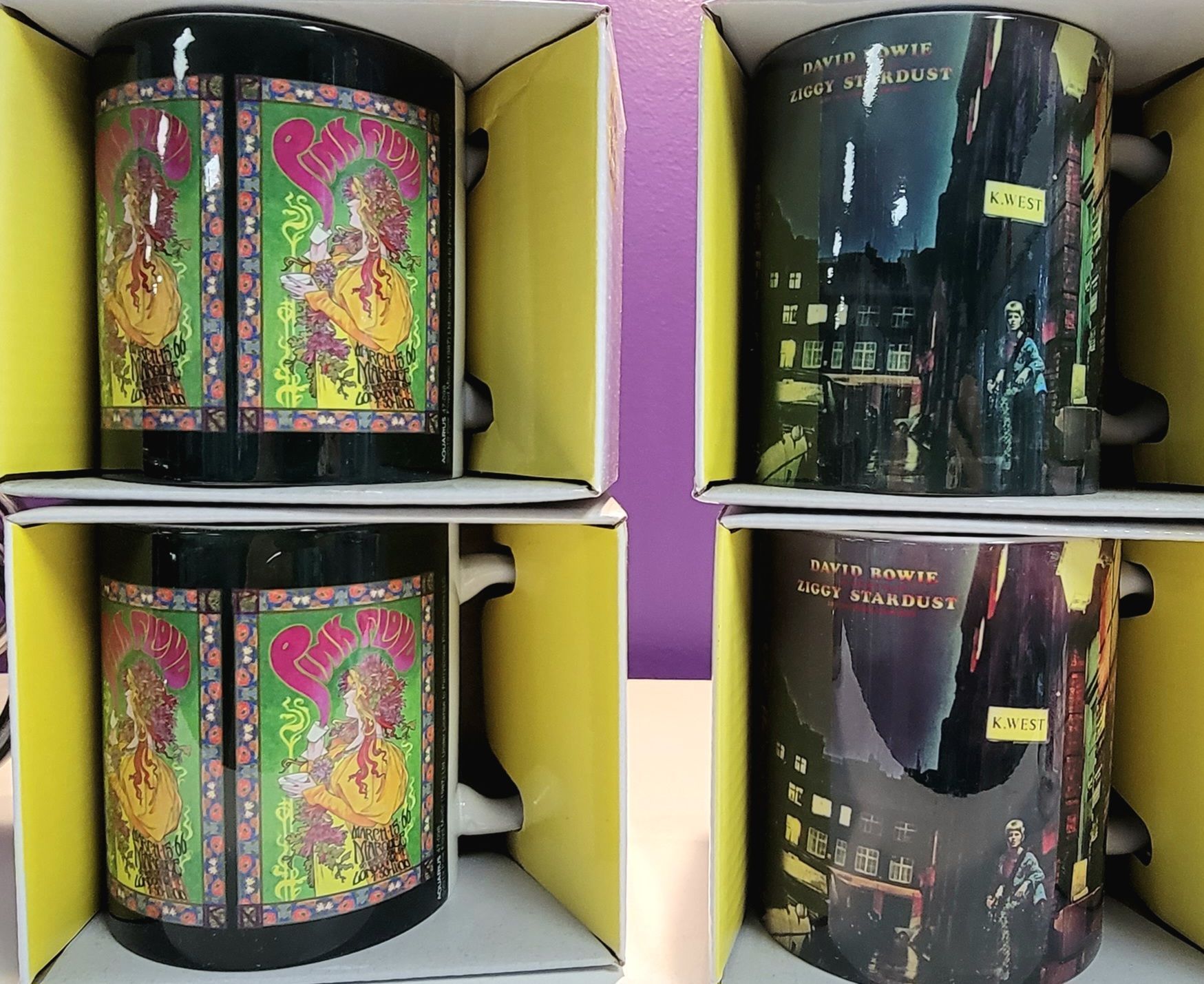 Four mugs in yellow boxes; two with a floral design and two with a city night scene.