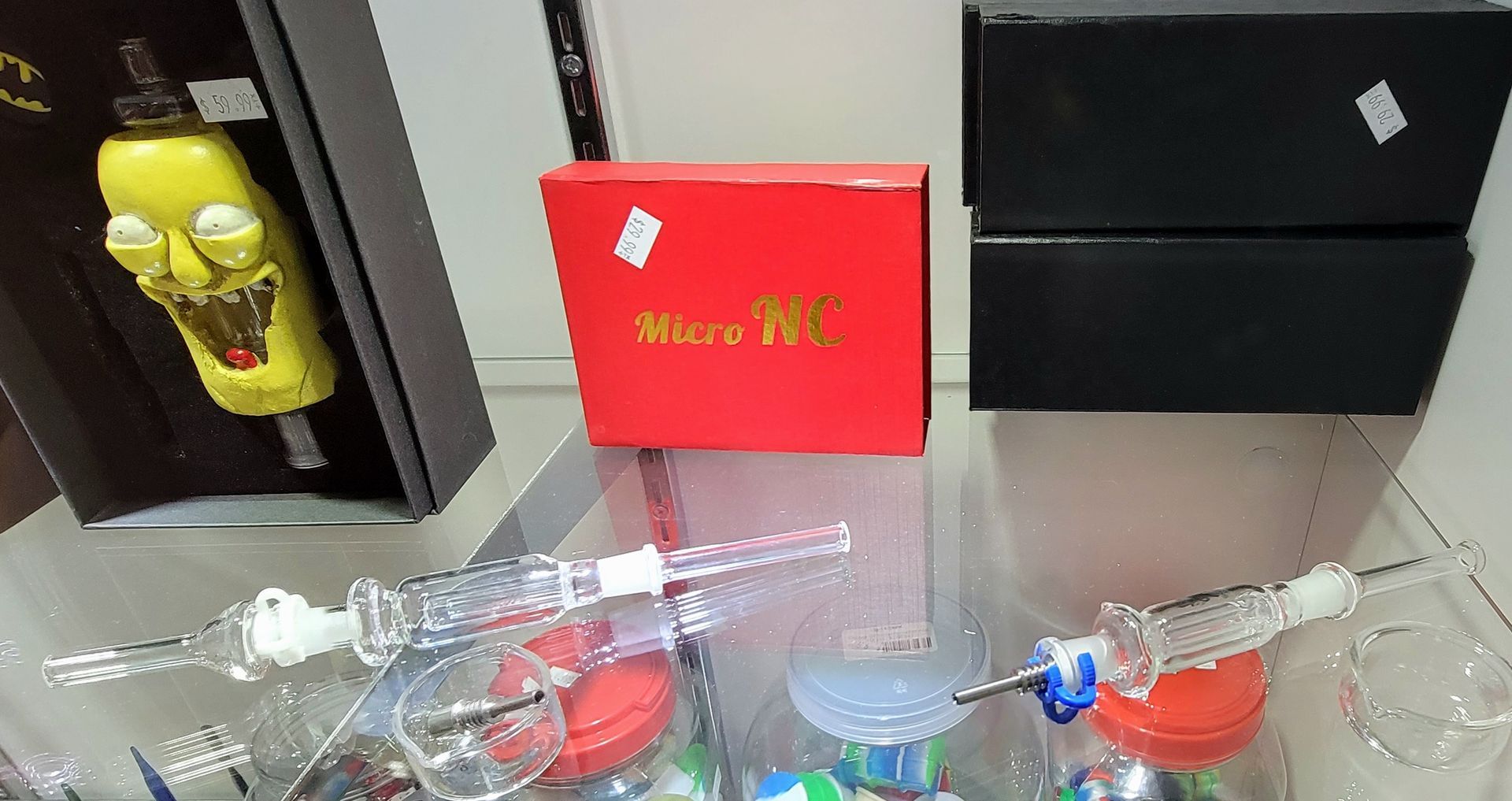 Display case with a novelty glass pipe, a red box, and glass smoking accessories.