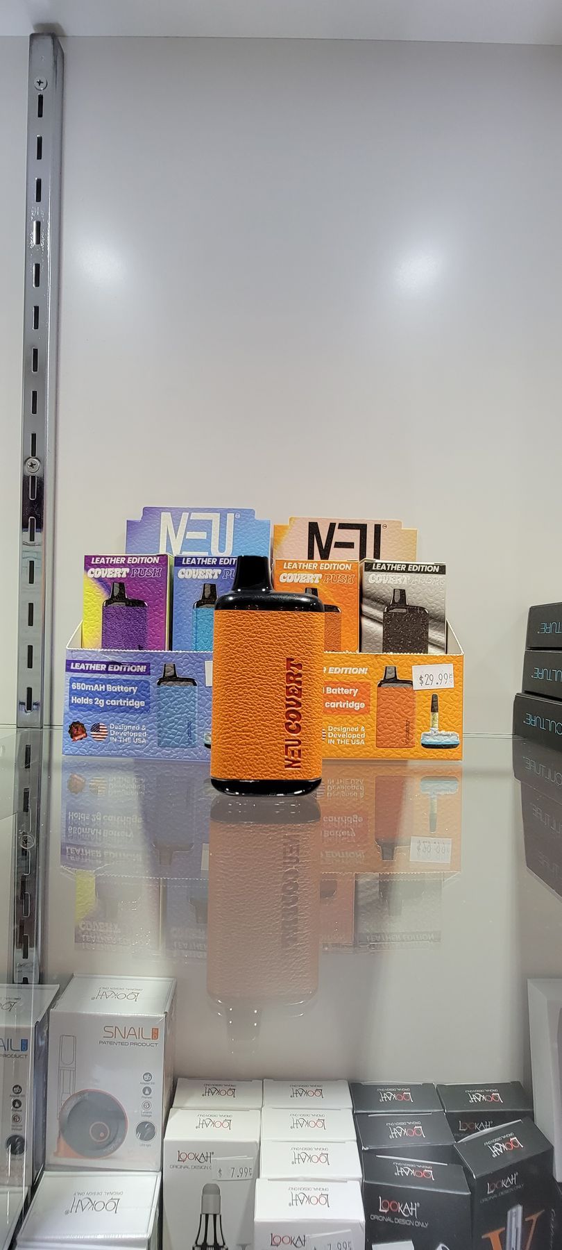 A shelf with various boxes of fragrances and a large orange device.