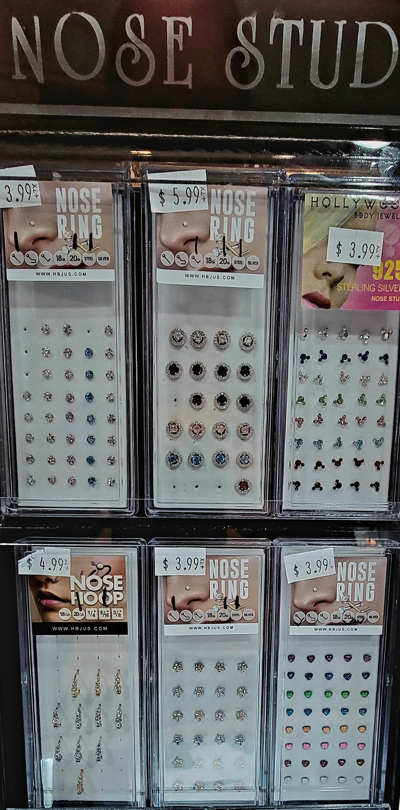Display of nose studs in a store; clear plastic packaging with a variety of stud styles.