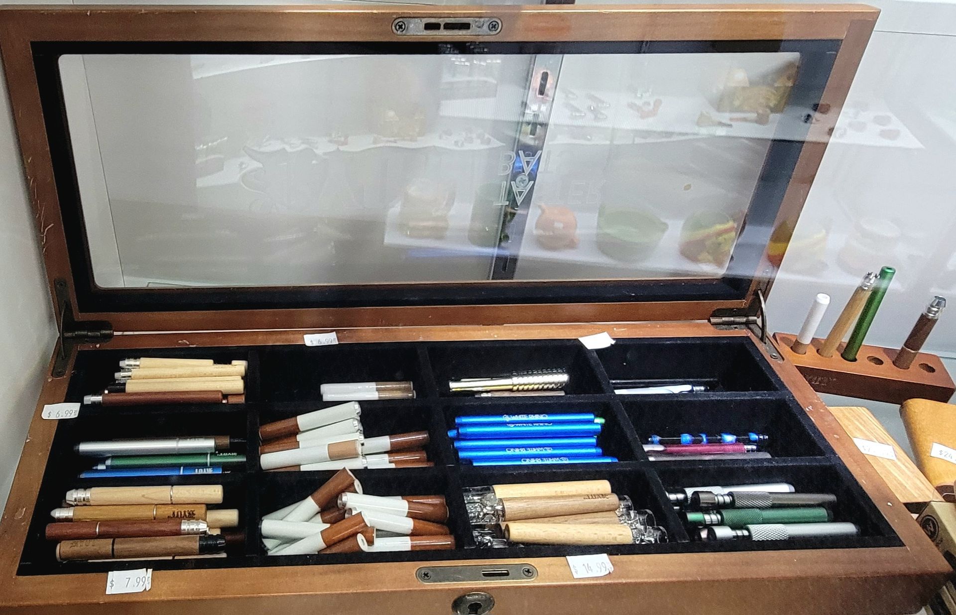 Wooden display case with pens of various colors and styles, viewed from above.