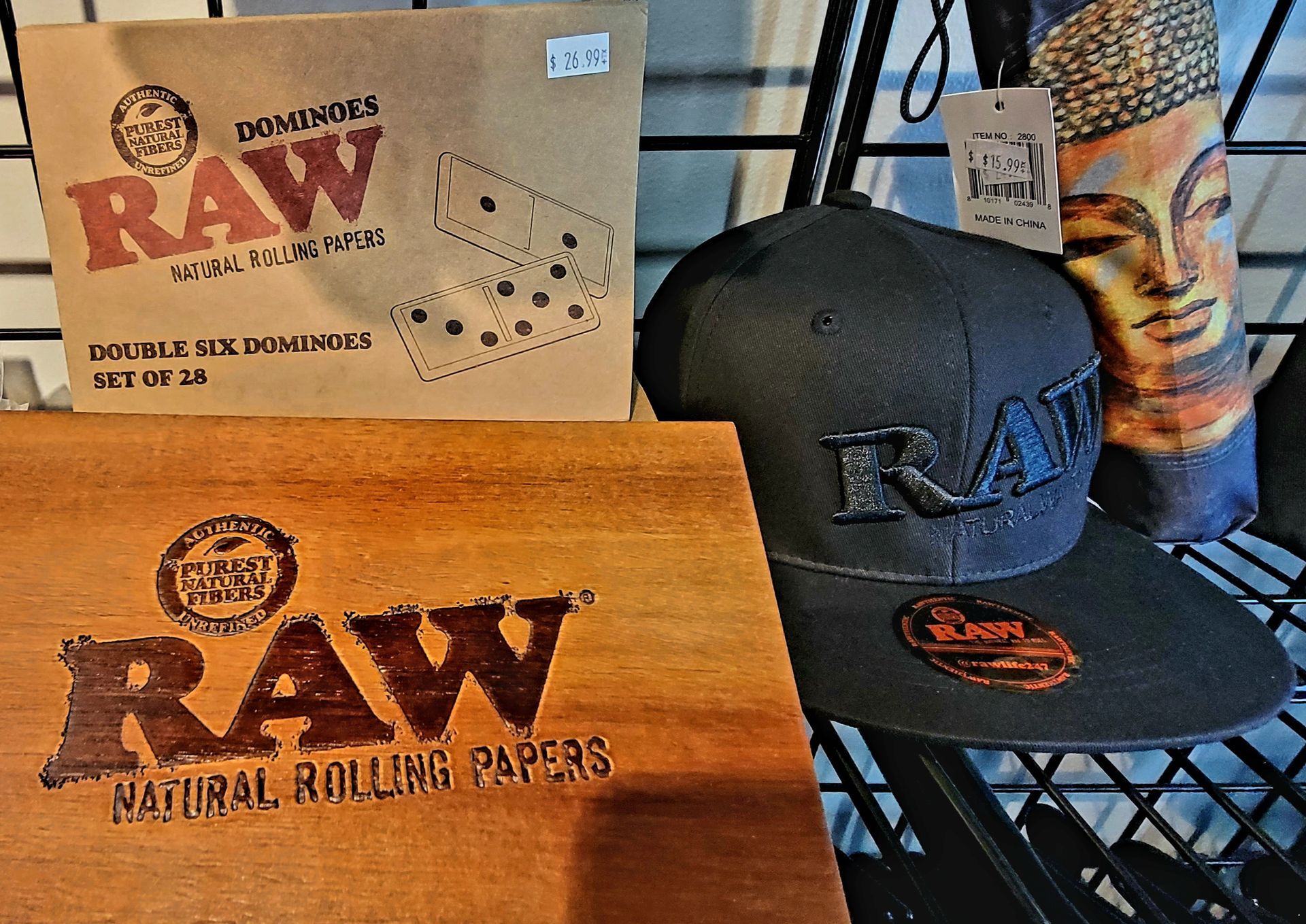 RAW rolling papers, dominoes, a hat, and a Buddha statue on display.