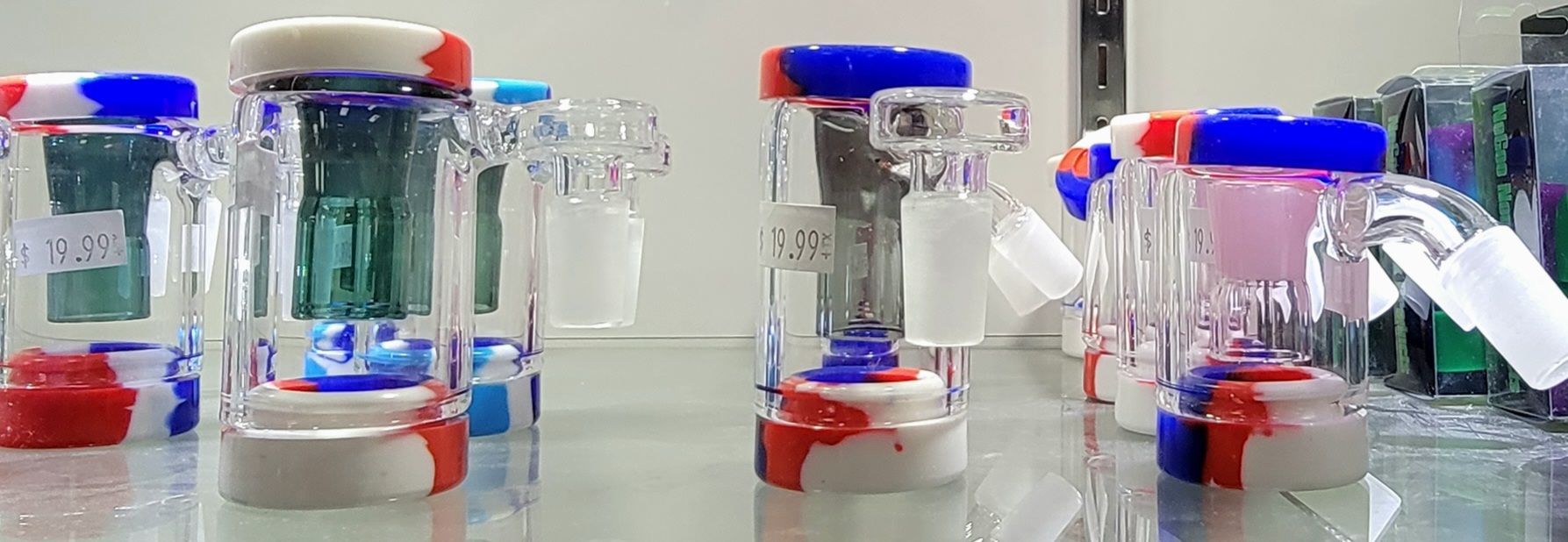 Glass bongs with red, white, and blue accents are lined up on a glass surface.