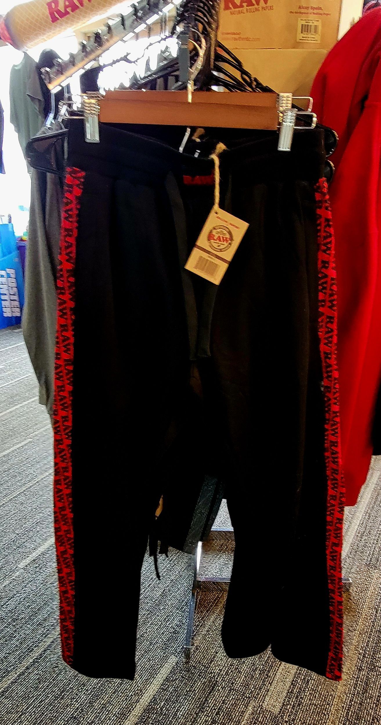 Black pants with red stripes hanging on a rack.