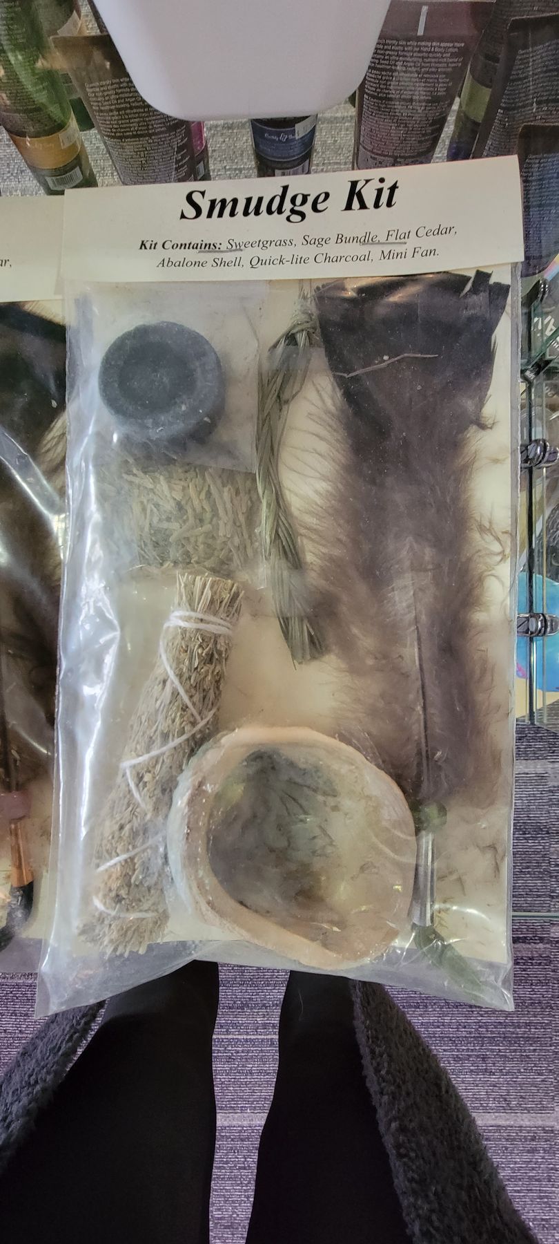 Smudge kit in a plastic bag, includes herbs, feather, shell and a small rock.