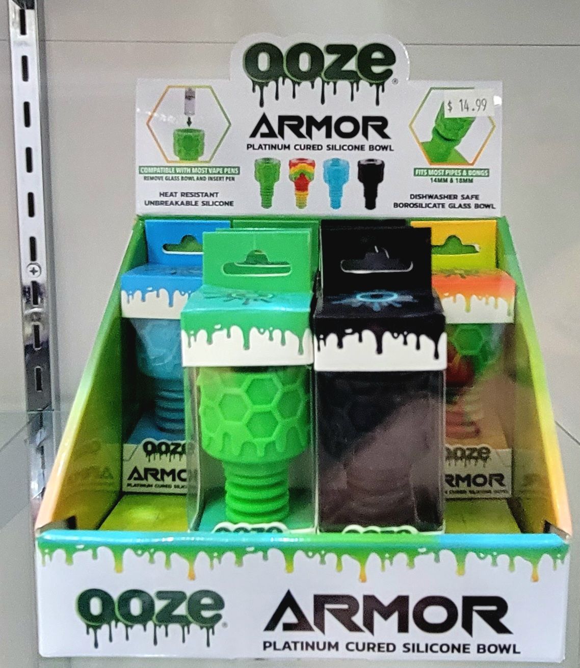 Display case with Ooze Armor silicone bowls in various colors, featuring branding and product information.