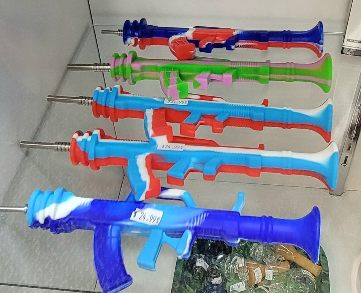 Colorful silicone dab rigs shaped like rocket launchers displayed on a shelf.