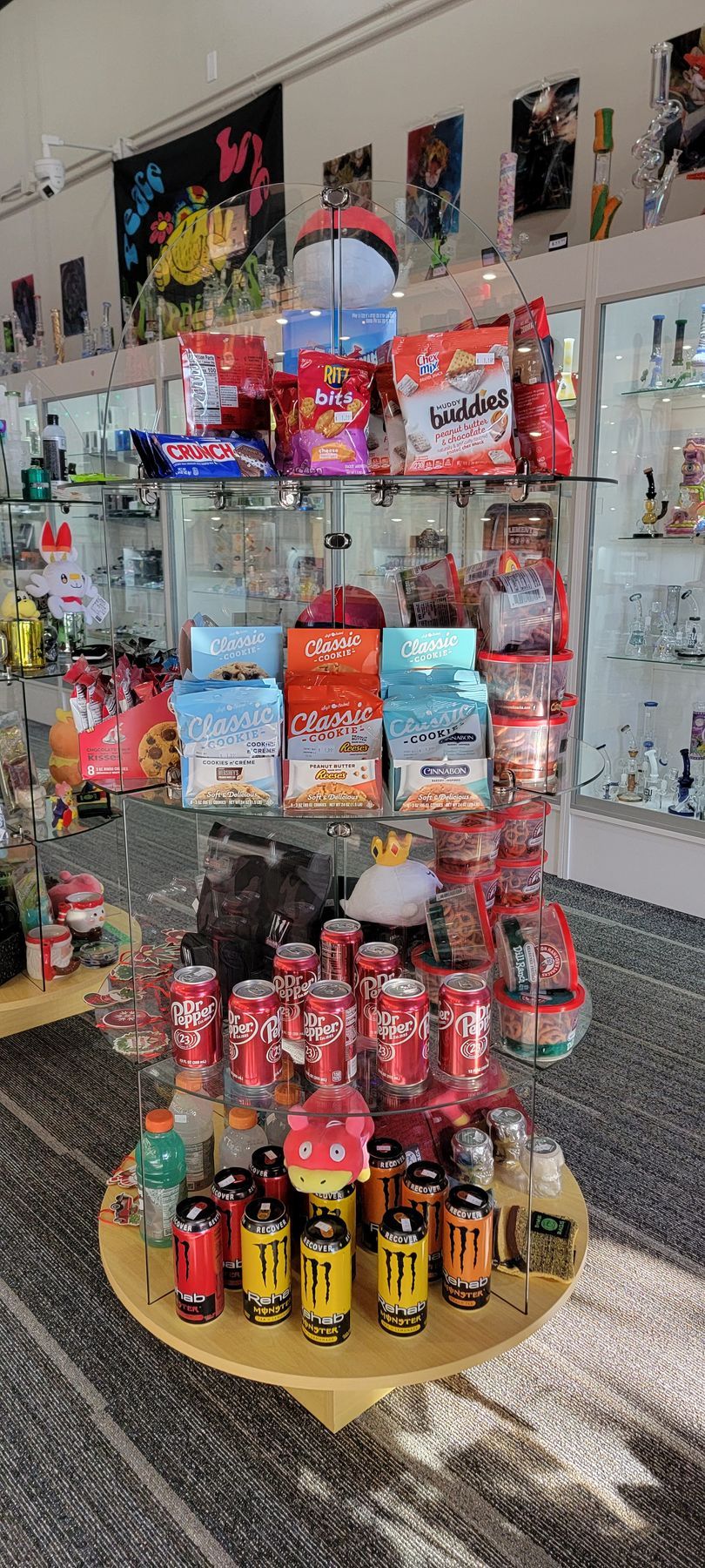 Display of snacks, drinks, and collectibles in a store, including soda cans, energy drinks, and bags of chips.