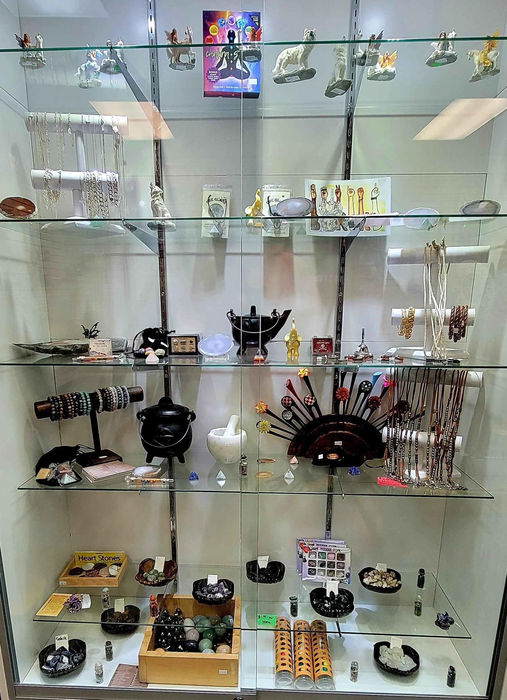 Glass display case with various items, including jewelry, figurines, and small decorative objects.