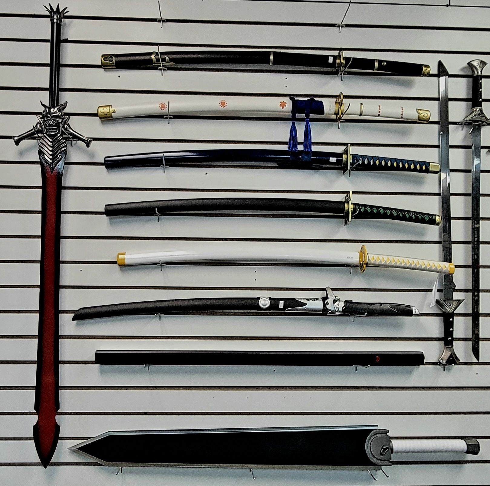 Collection of decorative swords displayed on a wall. Includes katana and fantasy swords in various styles and colors.