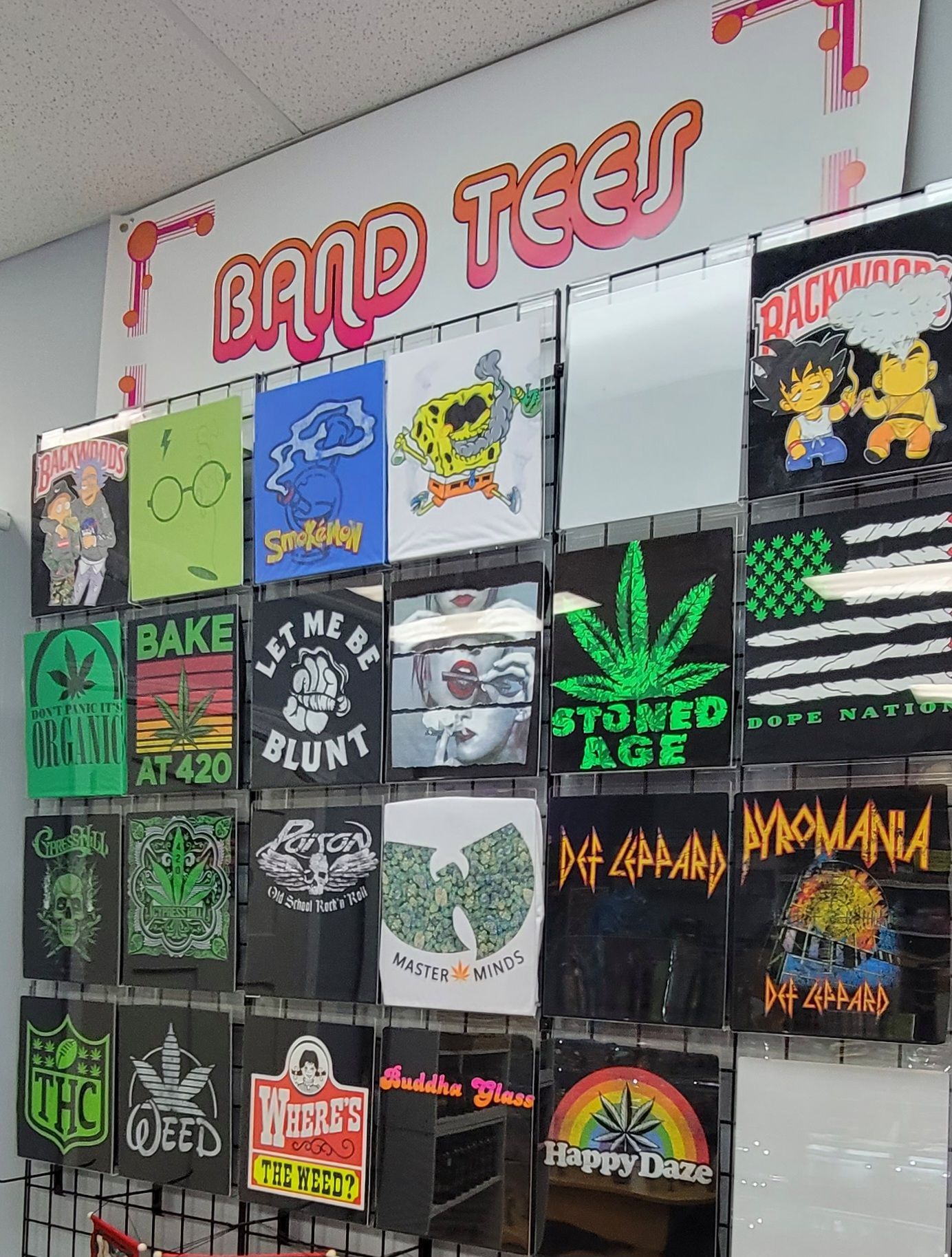 A display of band and graphic tees for sale. Featuring various logos, colors, and weed-related designs.