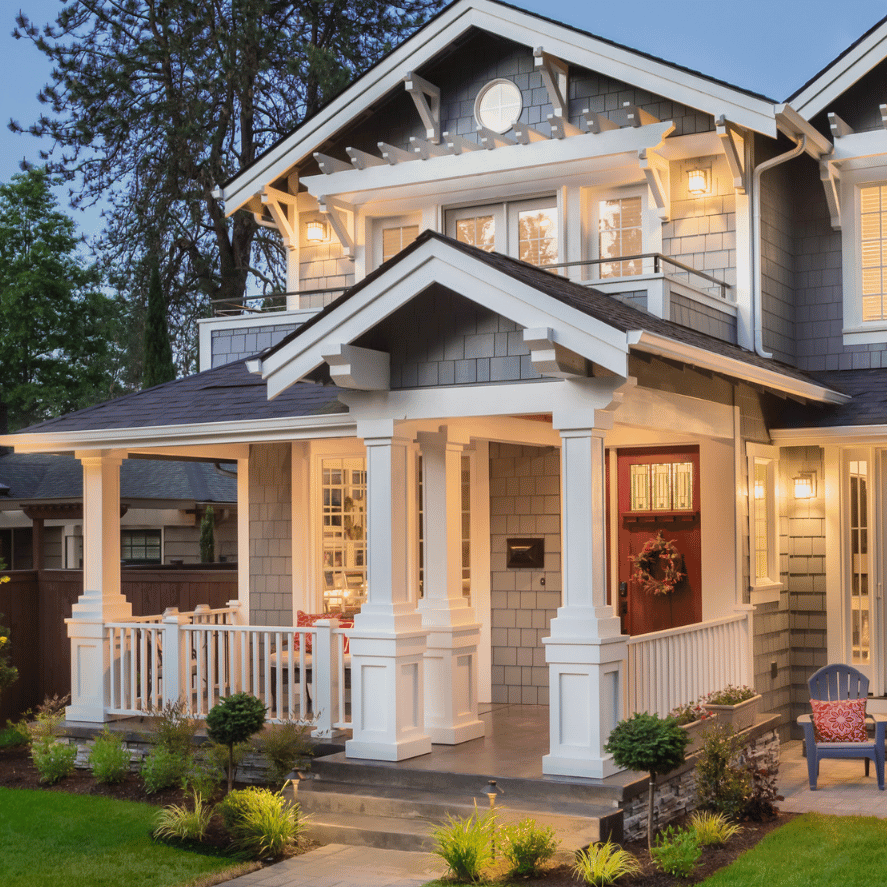 A large house with a large porch is lit up at night.