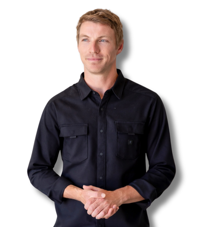 A man in a black shirt is standing with his hands folded