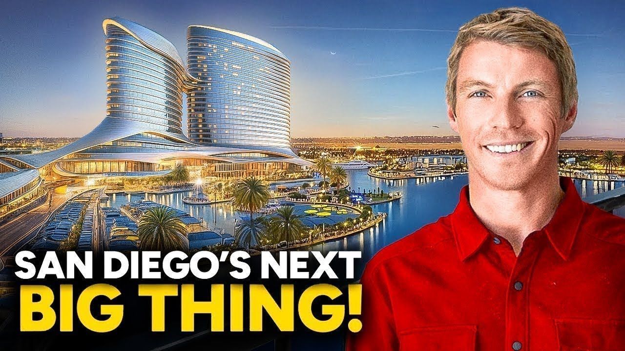 A man in a red shirt is standing in front of a large building.