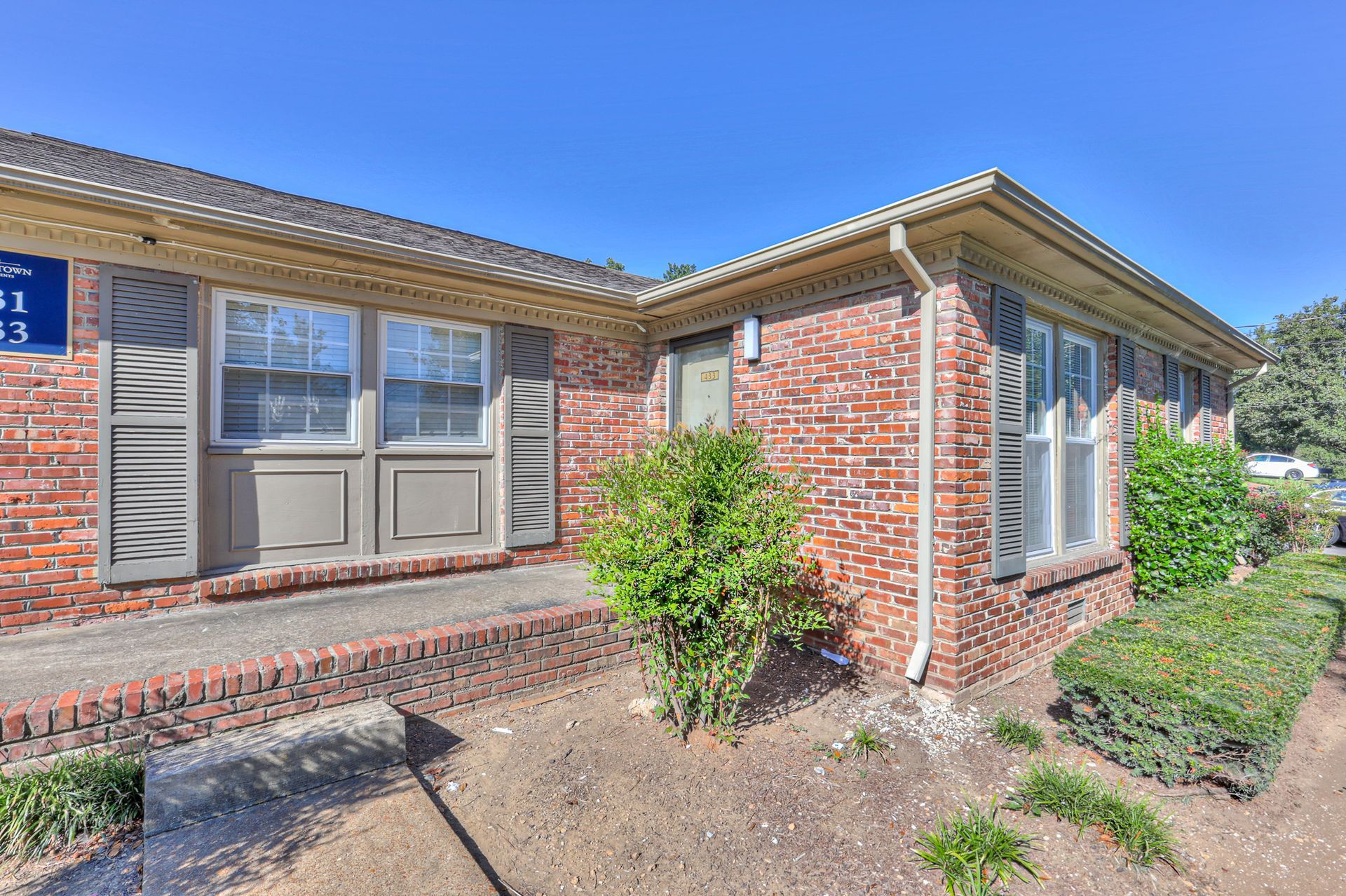 Photo of a red brick home with bushes outside