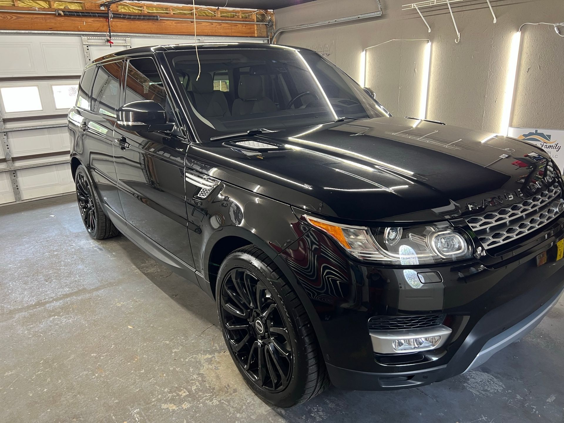 A black range rover sport is parked in a garage.