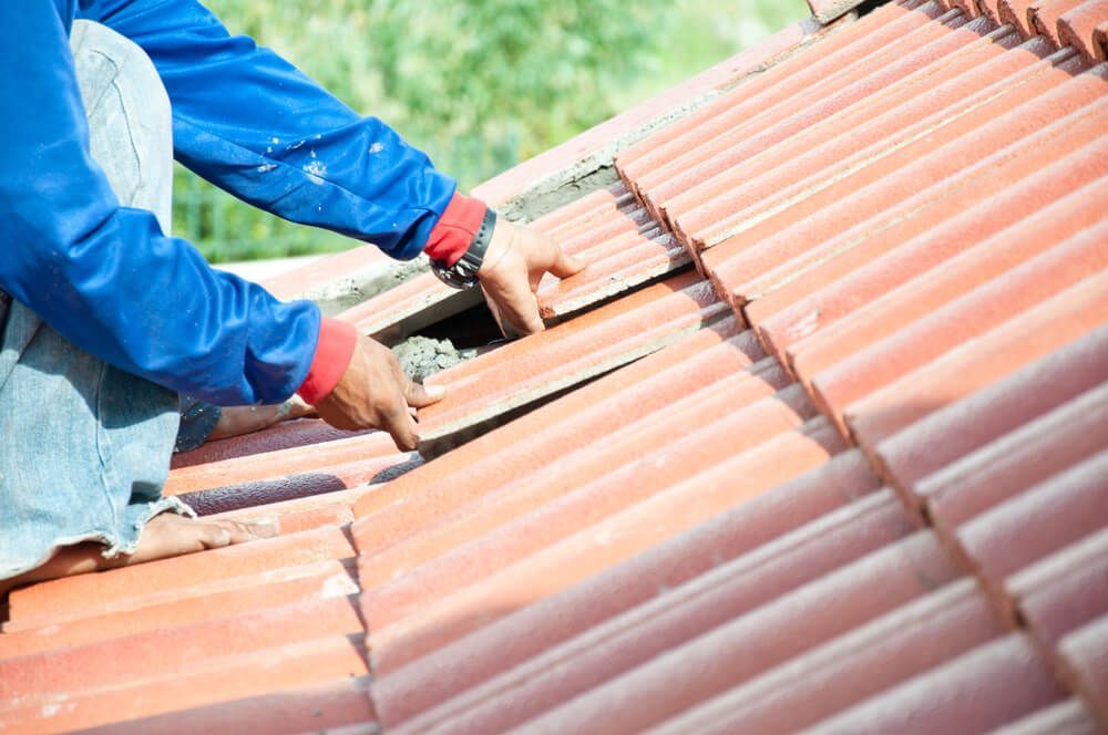 A Man is Installing Tiles on a Roof — QB Roof Tiling Services In Maroochydore, QLD