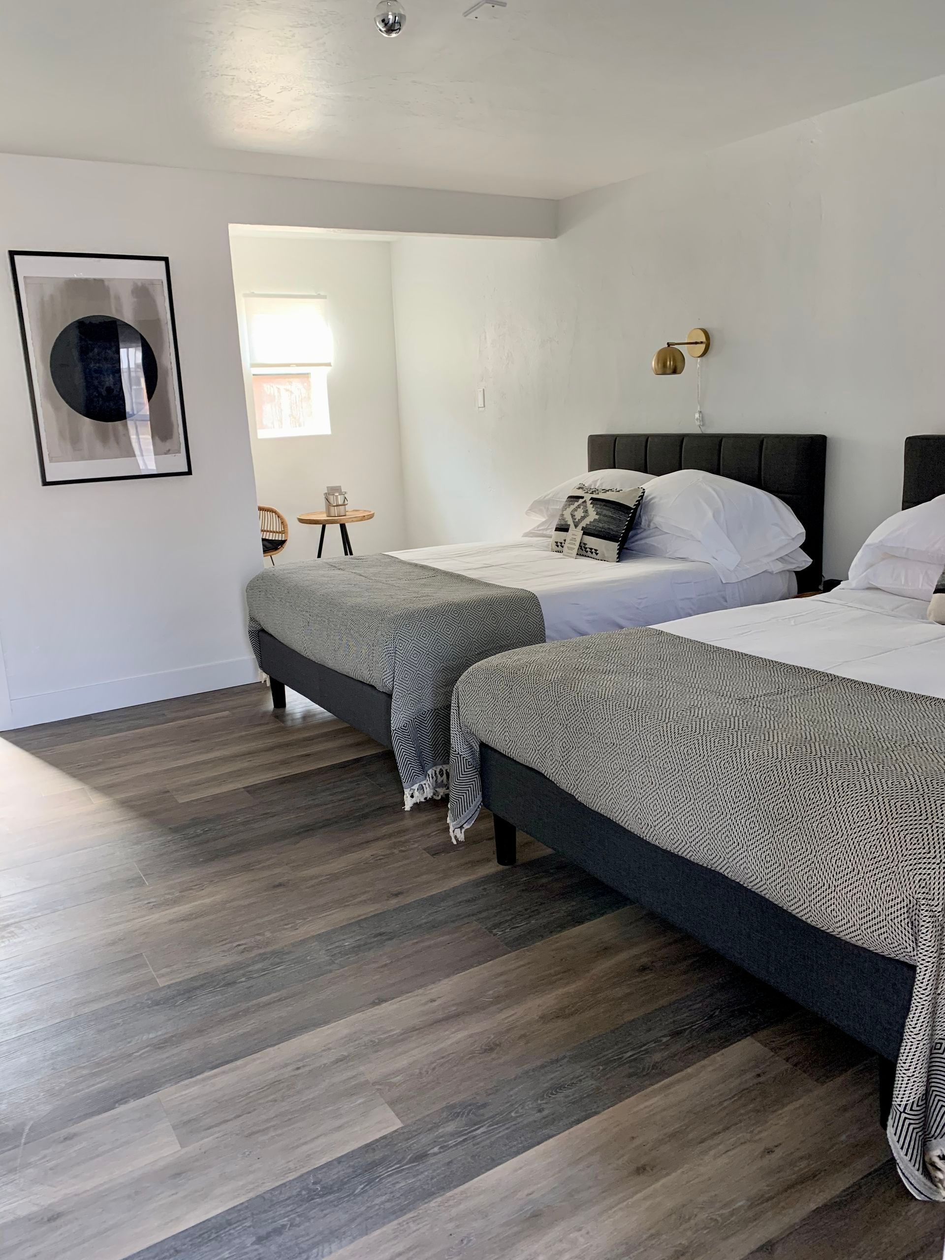 Two twin beds in a bright room with gray flooring, artwork, and modern decor.