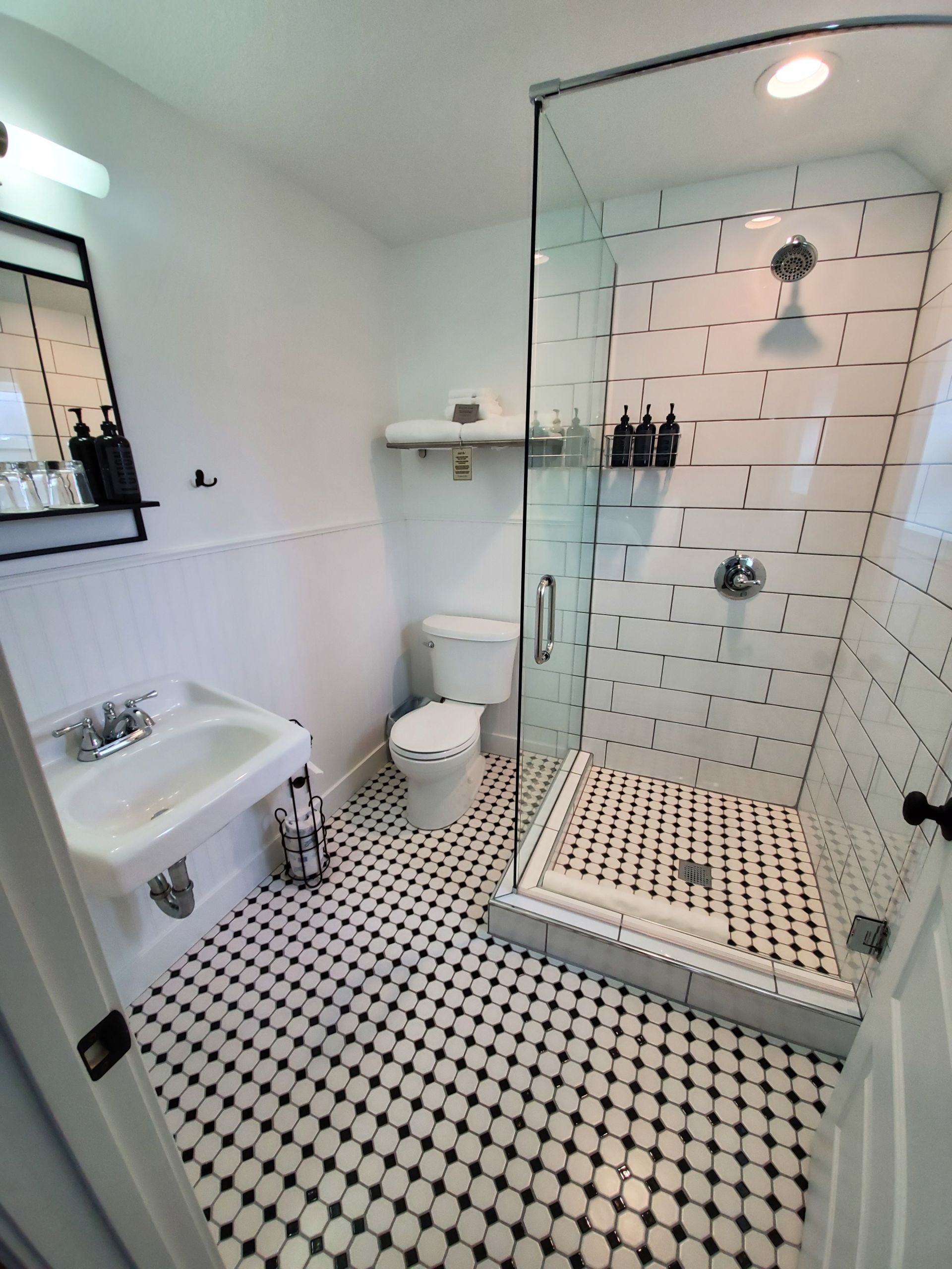 Bathroom with black and white patterned tile, white walls, and a glass shower.