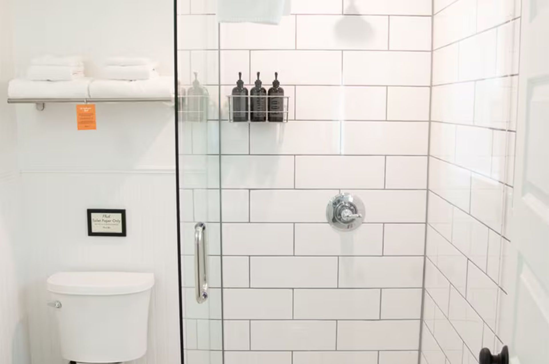 White bathroom with a toilet, shower, and towels.