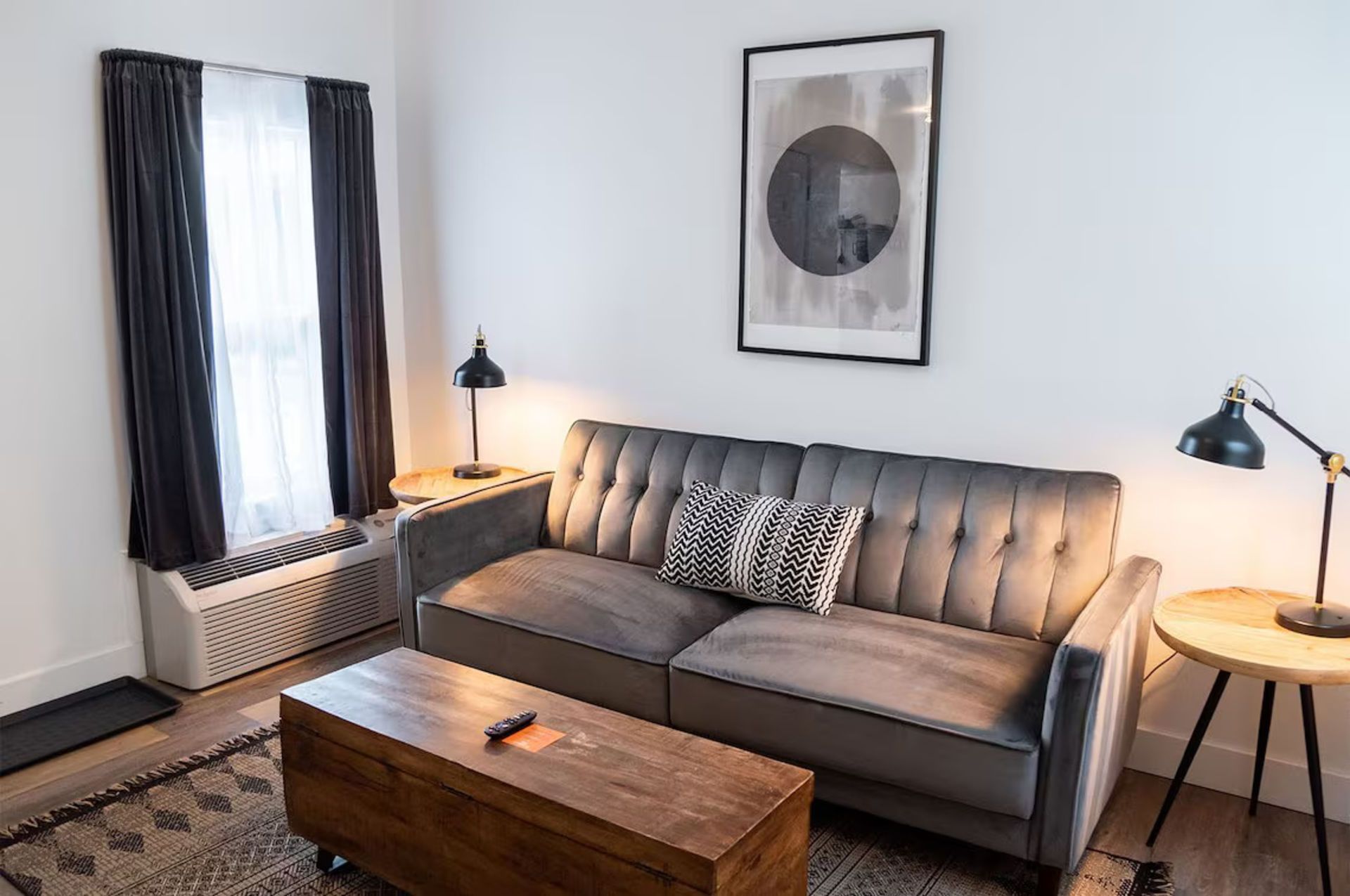 Living room with gray sofa, wooden coffee table, and a framed circle art print.