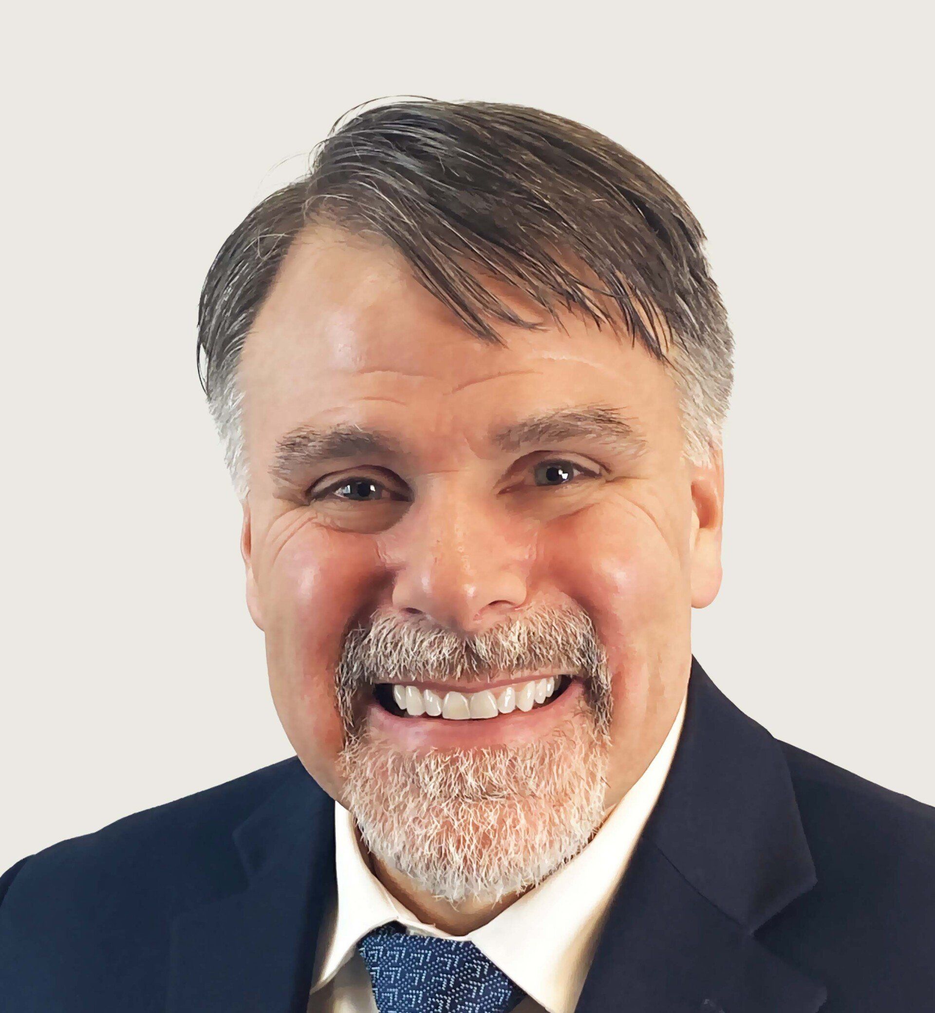 mark mangan is wearing a suit and tie and smiling.