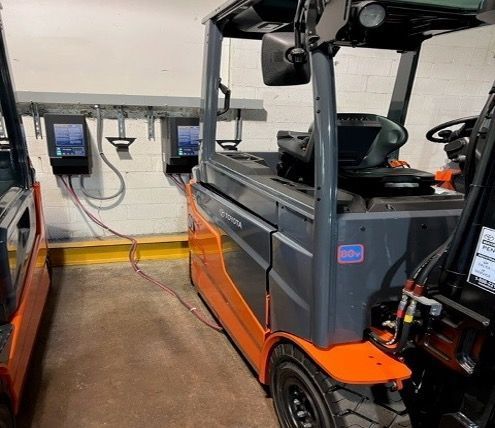 A forklift is sitting in a garage next to another forklift.