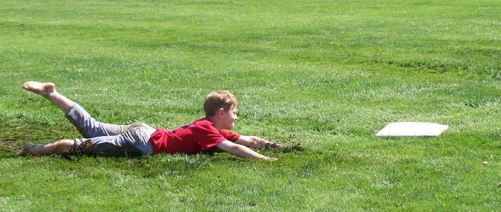 A young boy in a red shirt is laying in the grass playing with a frisbee.