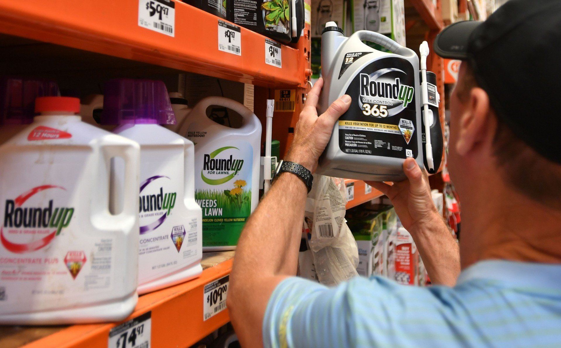 A man is holding a bottle of roundup in a store