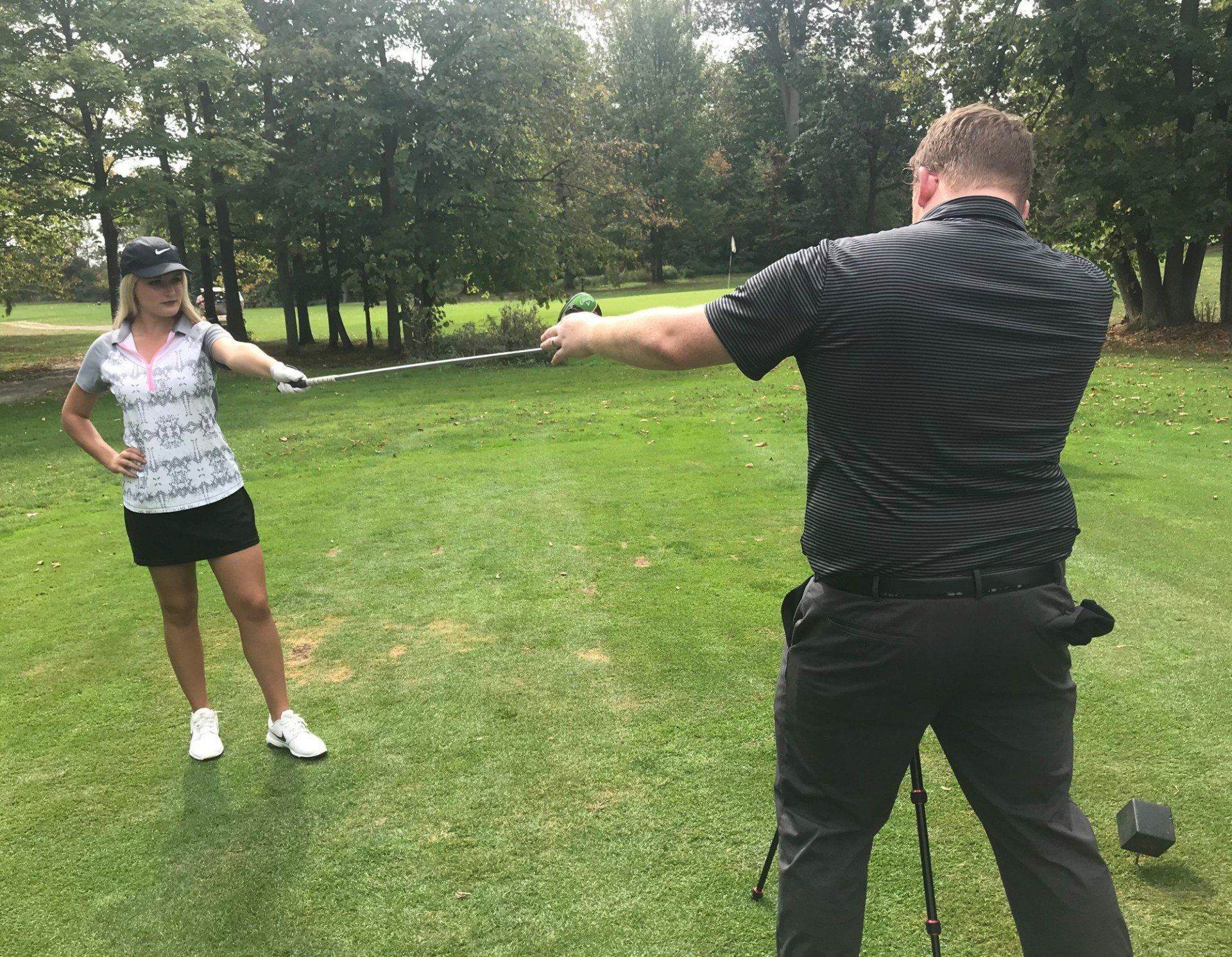 A man is showing nicole gerome how to pose for a image 