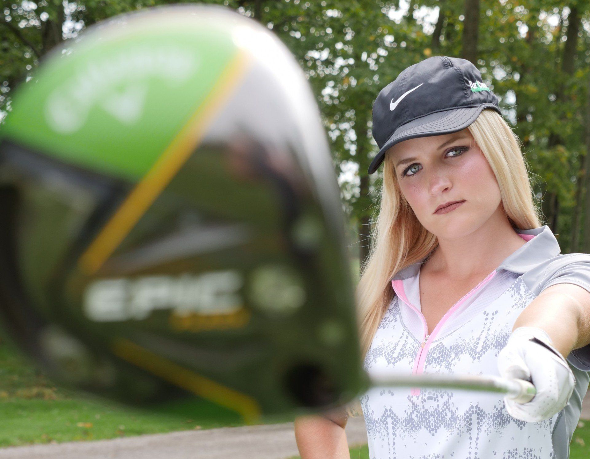 Nicole Gerome is holding a golf club in front of an epic golf club
