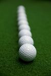 a row of golf balls on a green background
