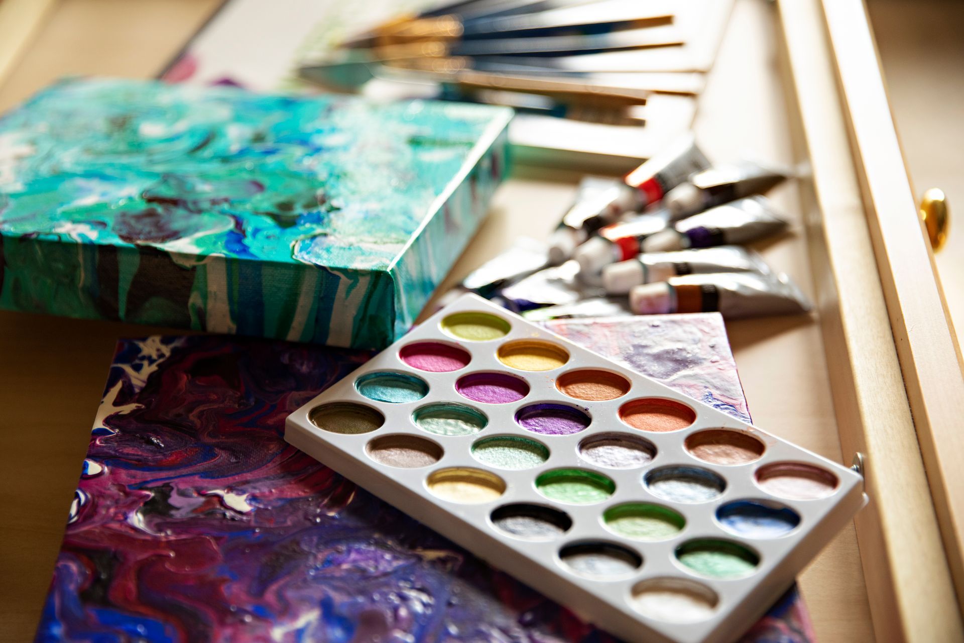 A palette of paint is sitting on a table next to a painting and brushes.