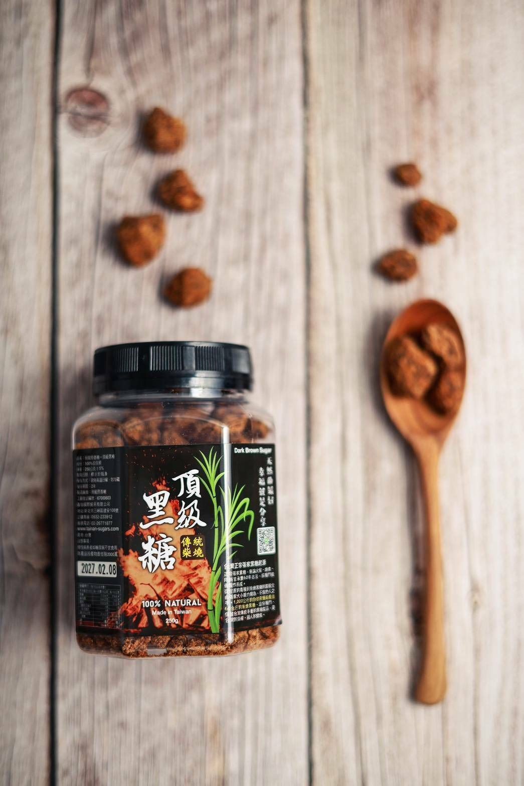 一罐紅糖塊，一把木勺，還有一些紅糖塊散落在木質表面上。