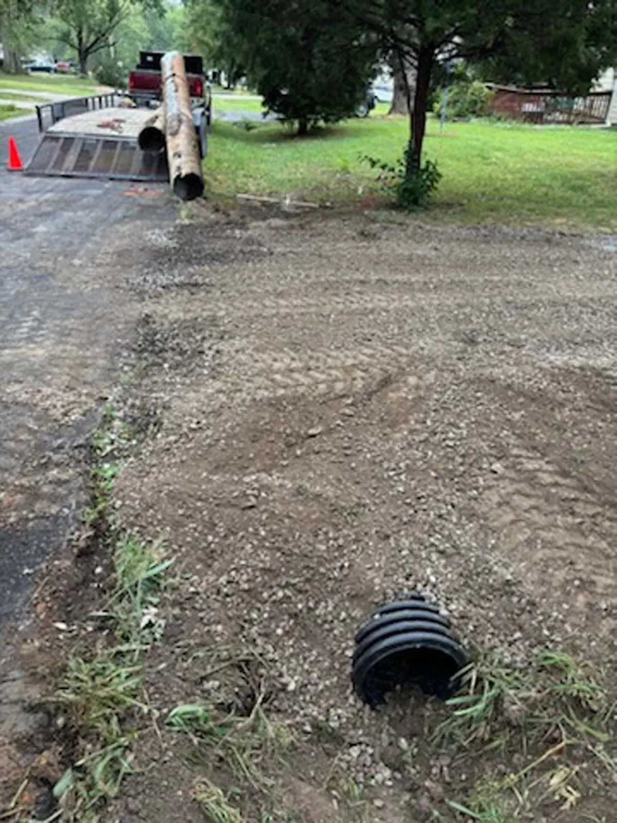 A truck is driving down a dirt road next to a pipe.