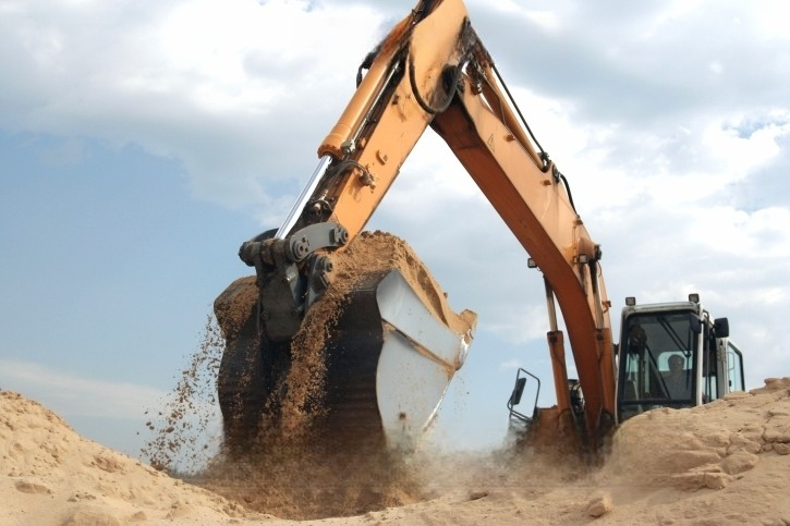 An excavator is digging a hole in the sand