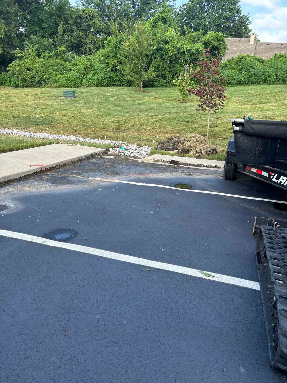 A dump truck is parked in a parking lot next to a grassy field.