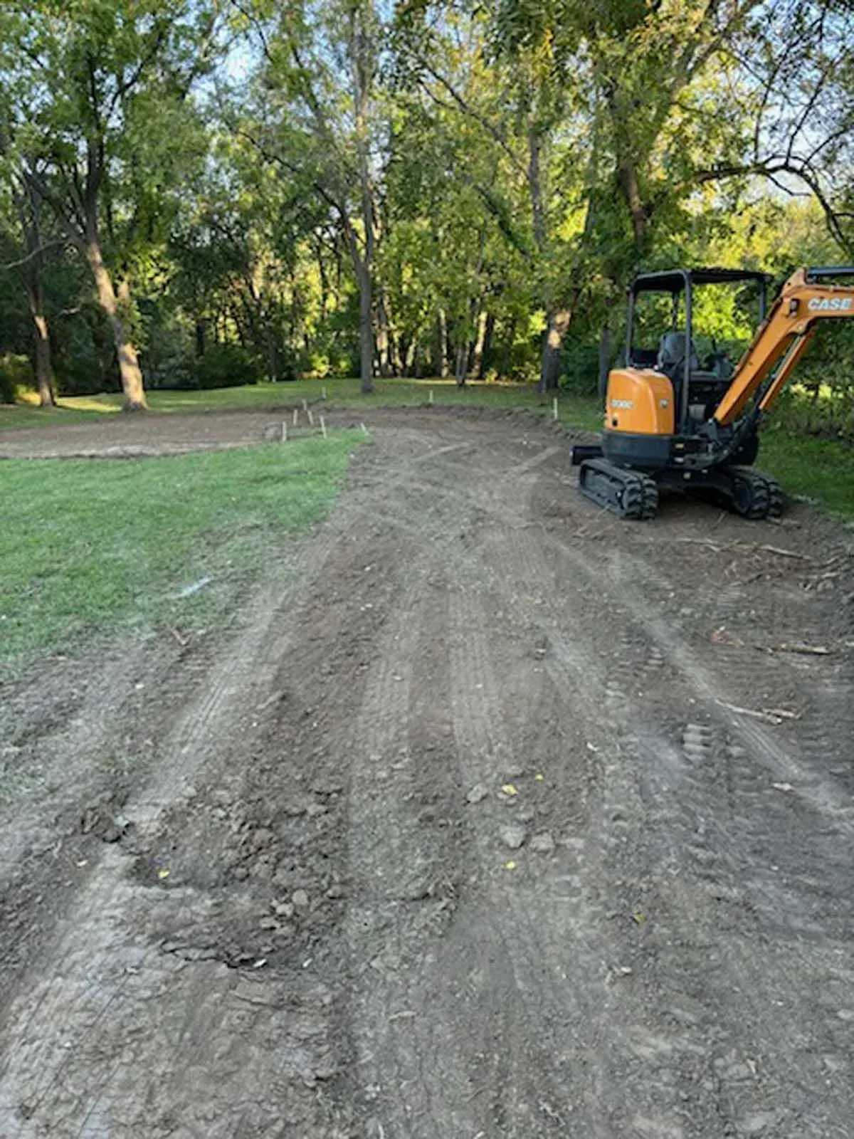 A small excavator is parked on the side of a dirt road.
