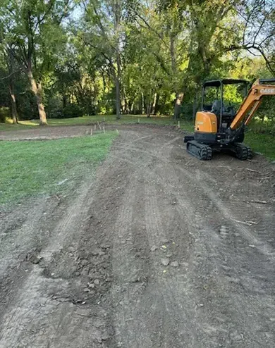 A small excavator is parked on the side of a dirt road.