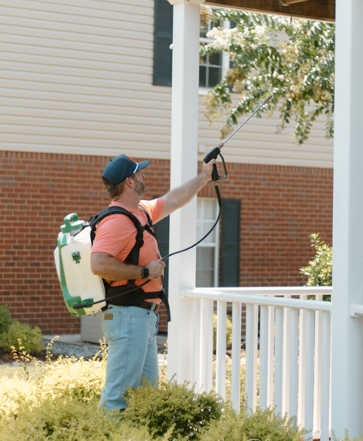 A man in a protective suit is spraying a room with a sprayer.
